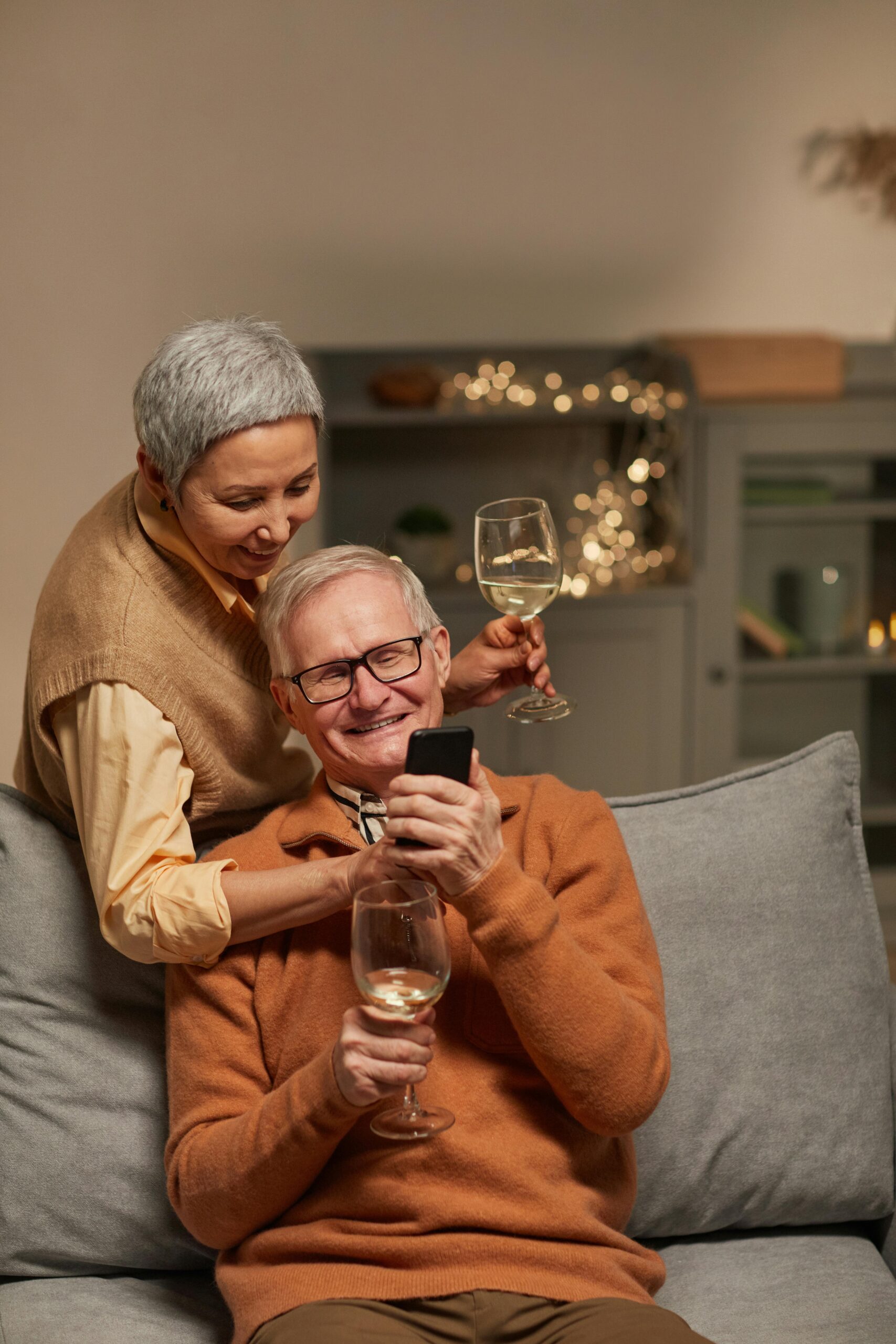 Couple enjoying a class of wine and smiling at the phone