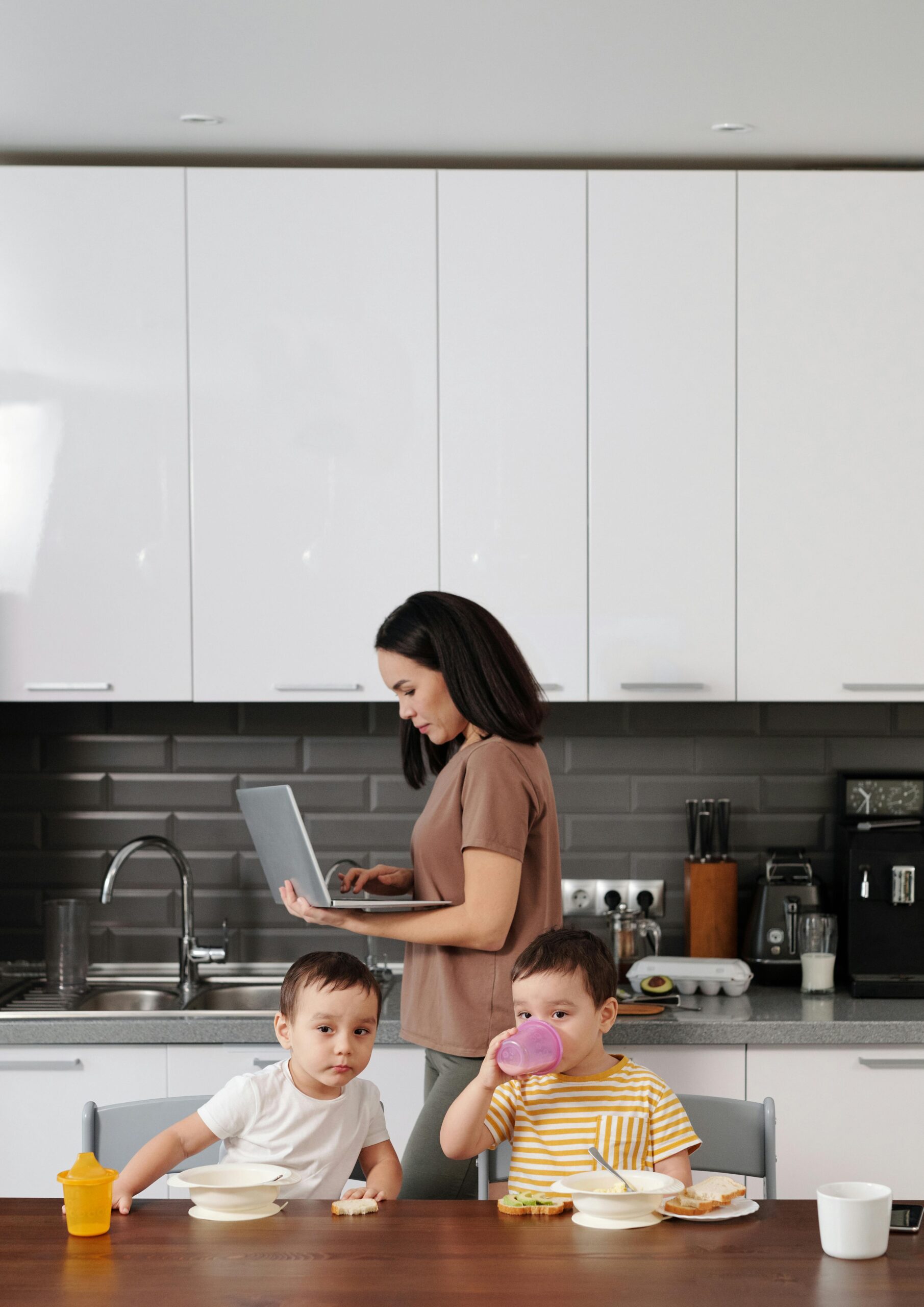 Mom working on laptop while kids eat breakfast