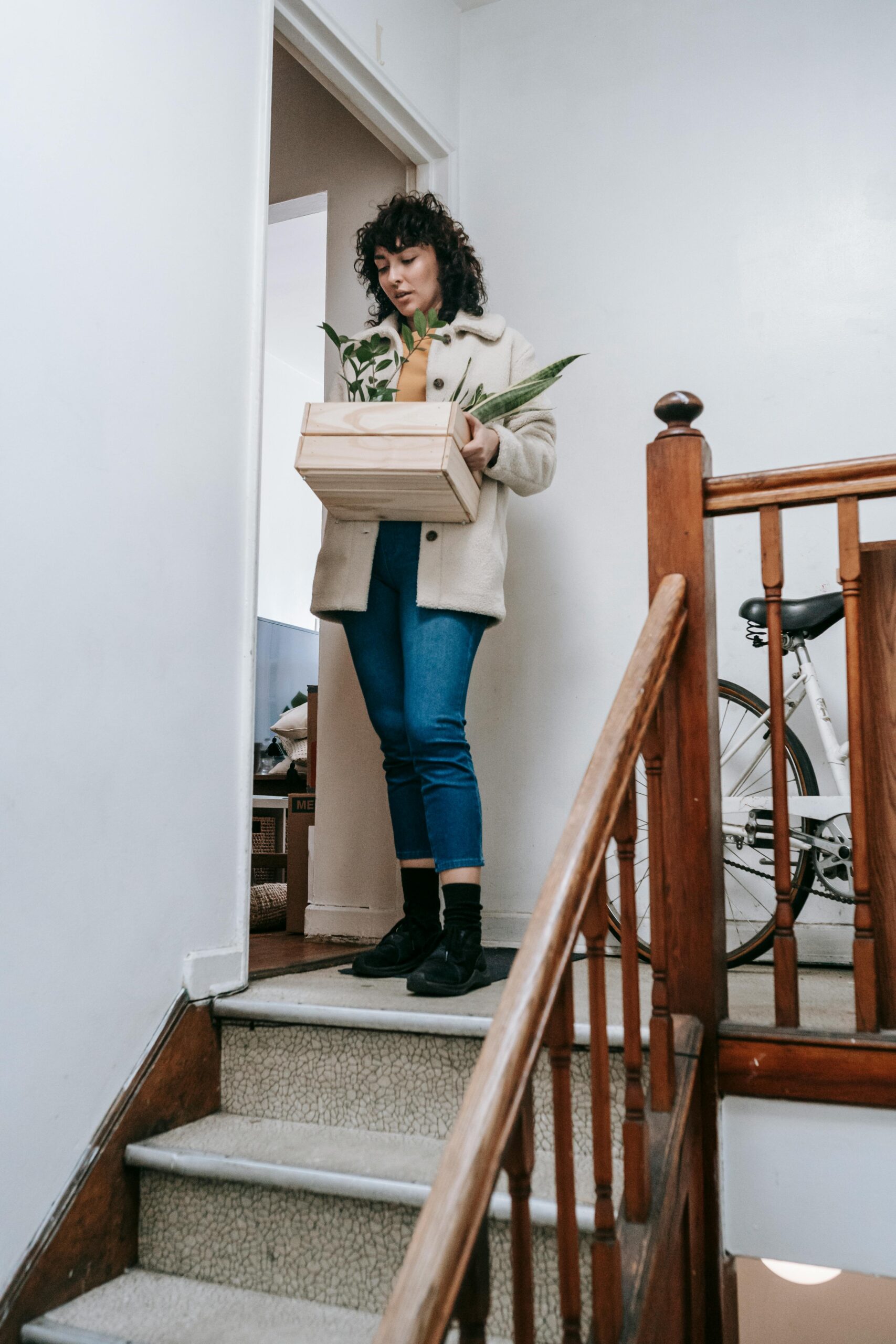 Woman going down the stairs with a box of plants