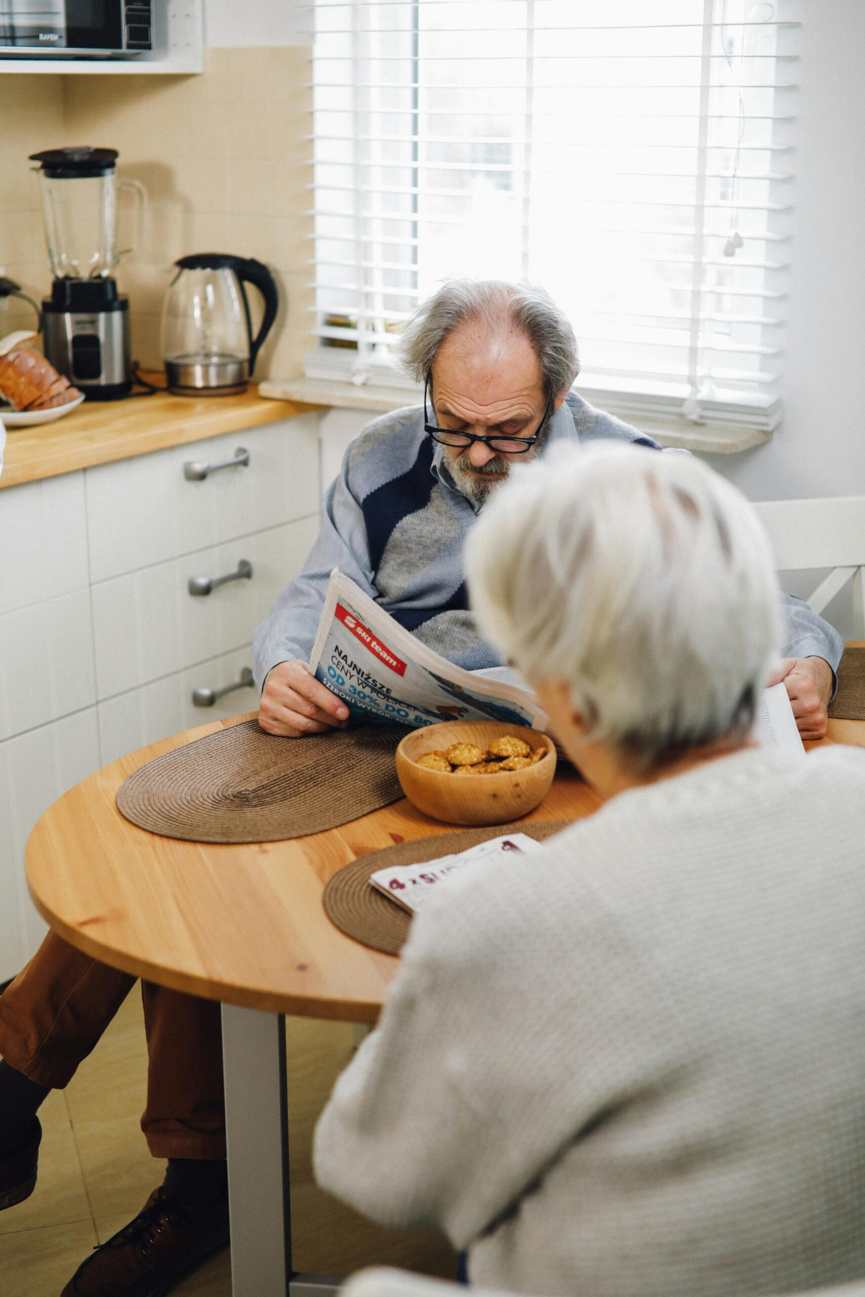 Elderly man reading newspaper at the dining table
