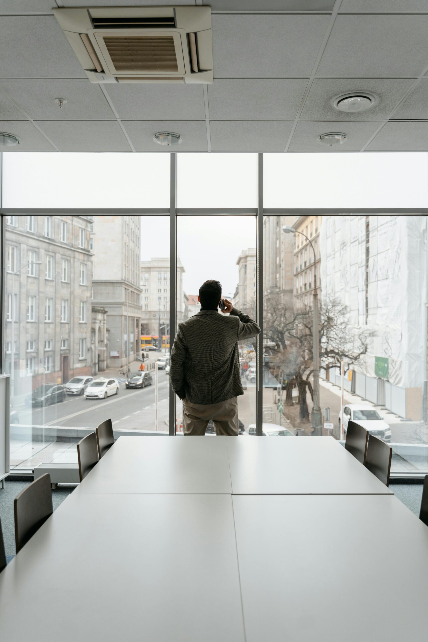 Man in an office looking out the window while talking on the phone