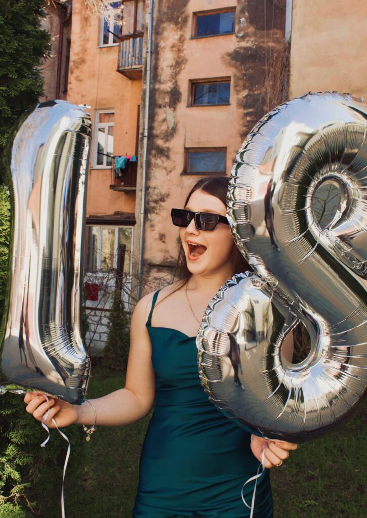 Young woman holding balloons that make the number eighteen